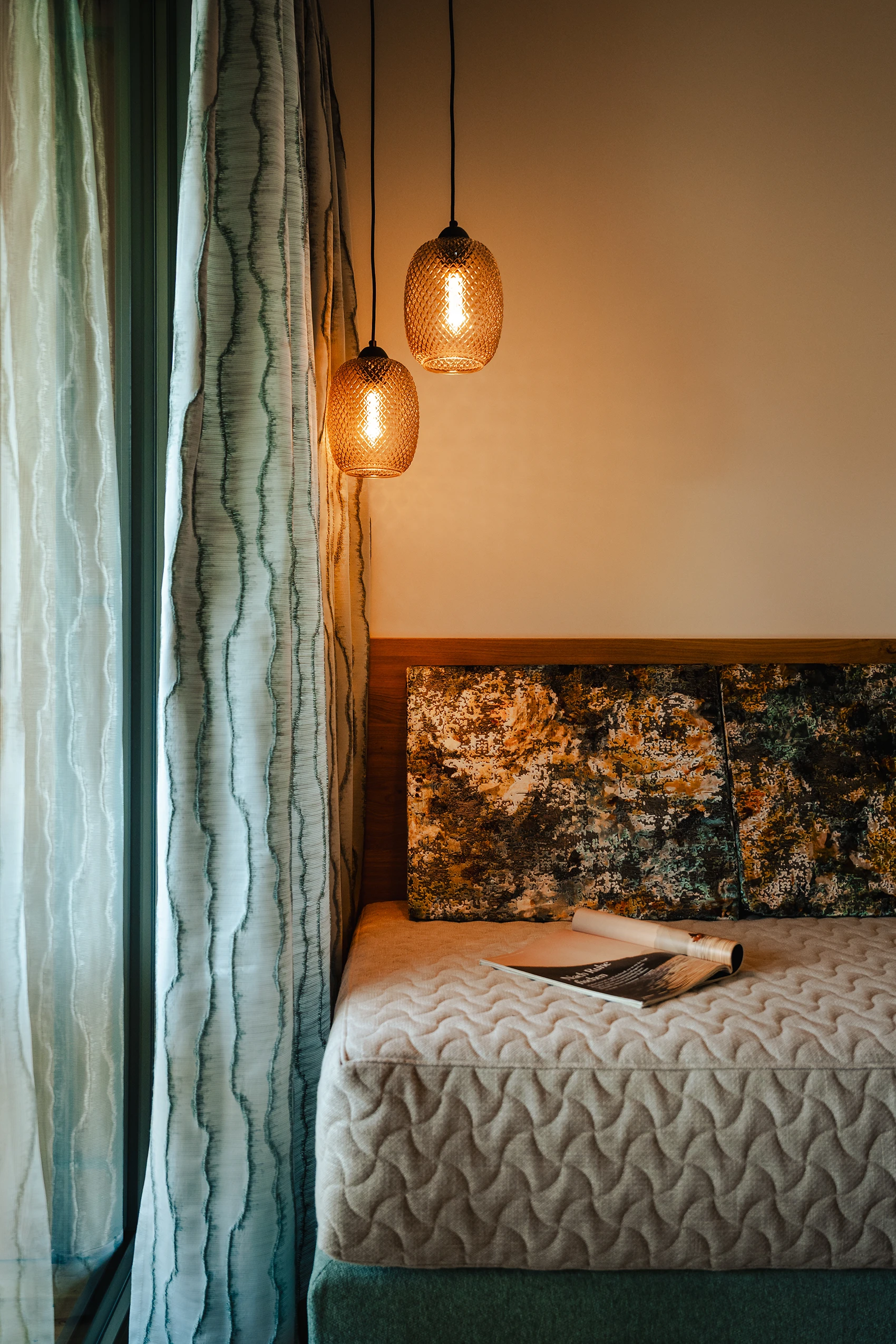 Detailfoto einer Bank in einem Zimmer des Naturparkhotels Weissensee Das Leonhard mit einer hängenden Lampe daneben.