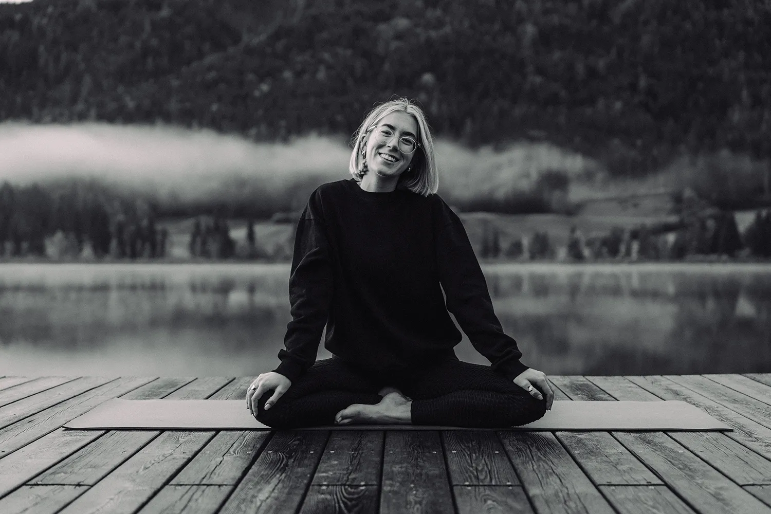 Ein lächelnder Yogi auf einer Terrasse am See, umrahmt von Bergen und Bäumen - maßgeschneiderte Inhalte für herausragende soziale Kampagnen von SquadTwenty. – SquadTwenty Werbeagentur Kärnten