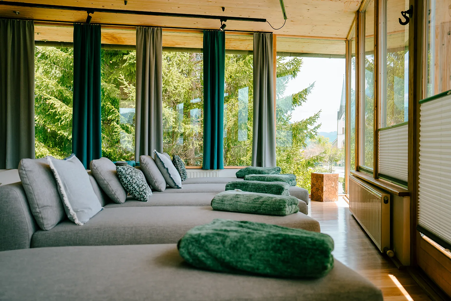 Sonnendurchflutete Loungesessel mit eleganten grauen Oberflächen und grünen Akzenten säumen einen hellen Raum, der die Kreativität in Bezug auf Inhalte und Markendesign anregt. – SquadTwenty Werbeagentur Kärnten