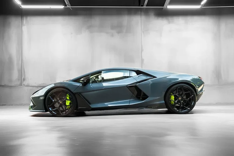Ein auffallend grauer Meyer-Hafner Lamborghini, akzentuiert durch schwarze Räder und leuchtend grüne Bremssättel, ruht in einem Innenraum unter greller Beleuchtung. – SquadTwenty Werbeagentur Kärnten