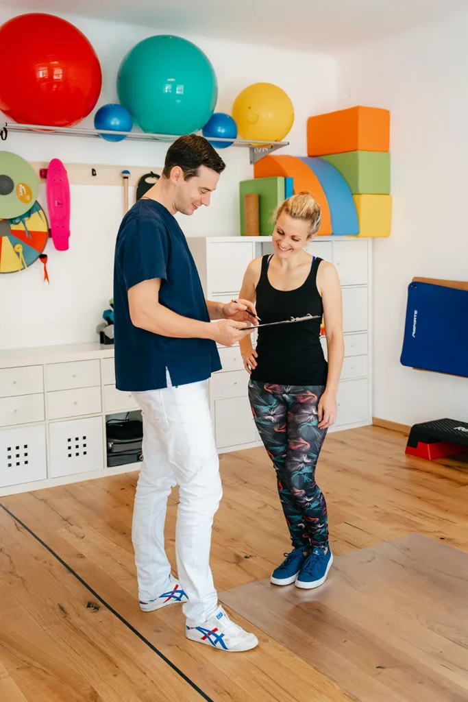 In einem lebhaften Fitnessstudio, mit einem Klemmbrett in der Hand, entwickelt ein Stratege Ideen für das Markendesign mit einem fröhlichen, sportlich gekleideten Kunden. – SquadTwenty Werbeagentur Kärnten